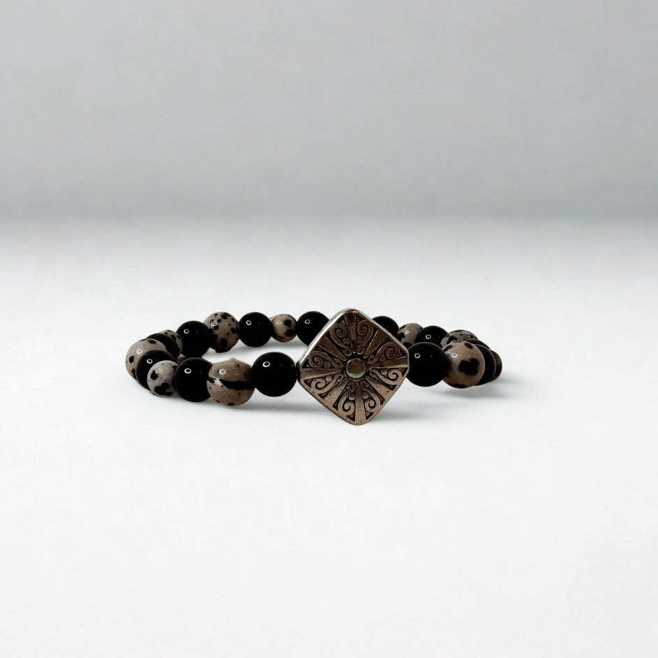 Black beaded bracelet with a bronze square pendant on a white background
