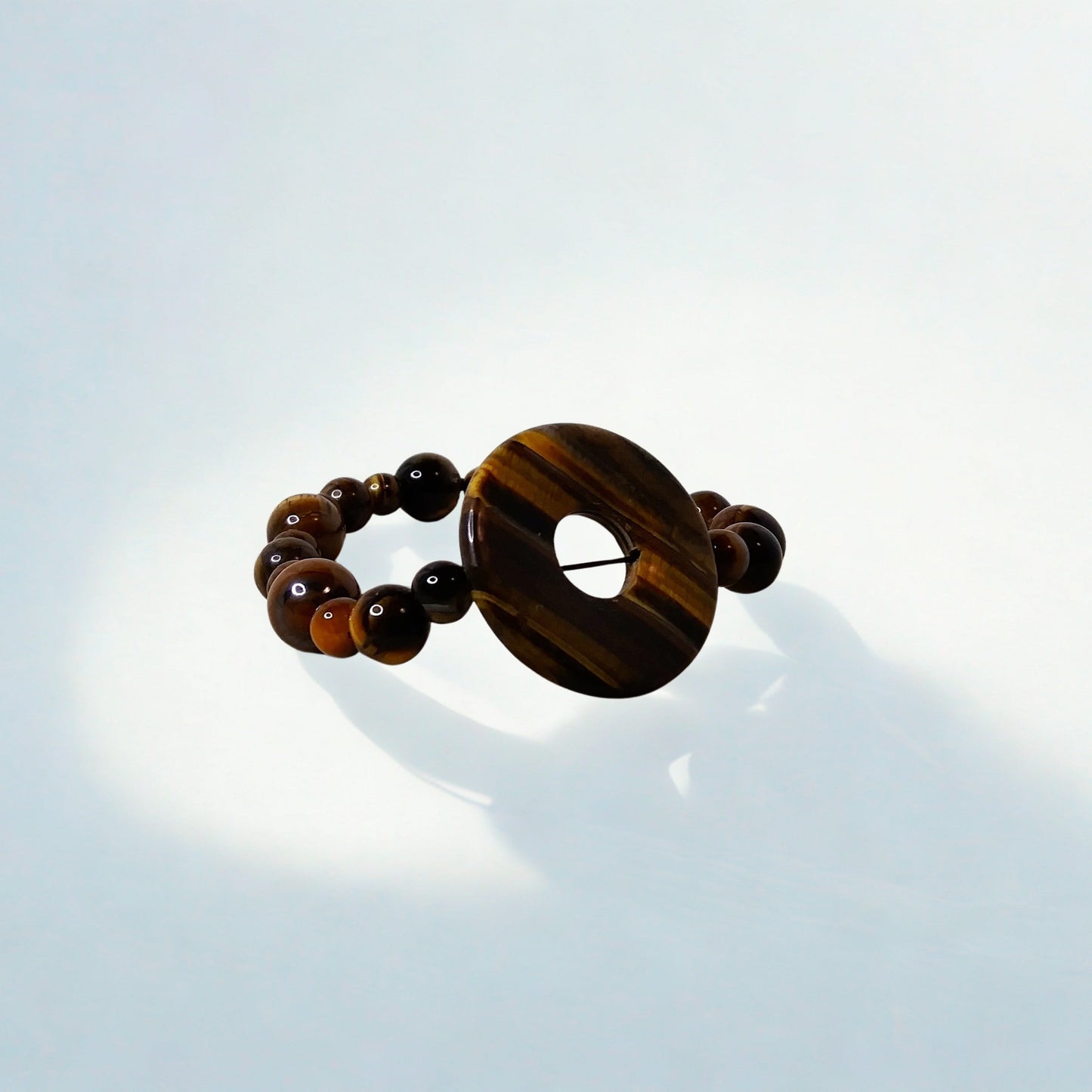 Tiger eye bracelet on a reflective surface with a light blue background