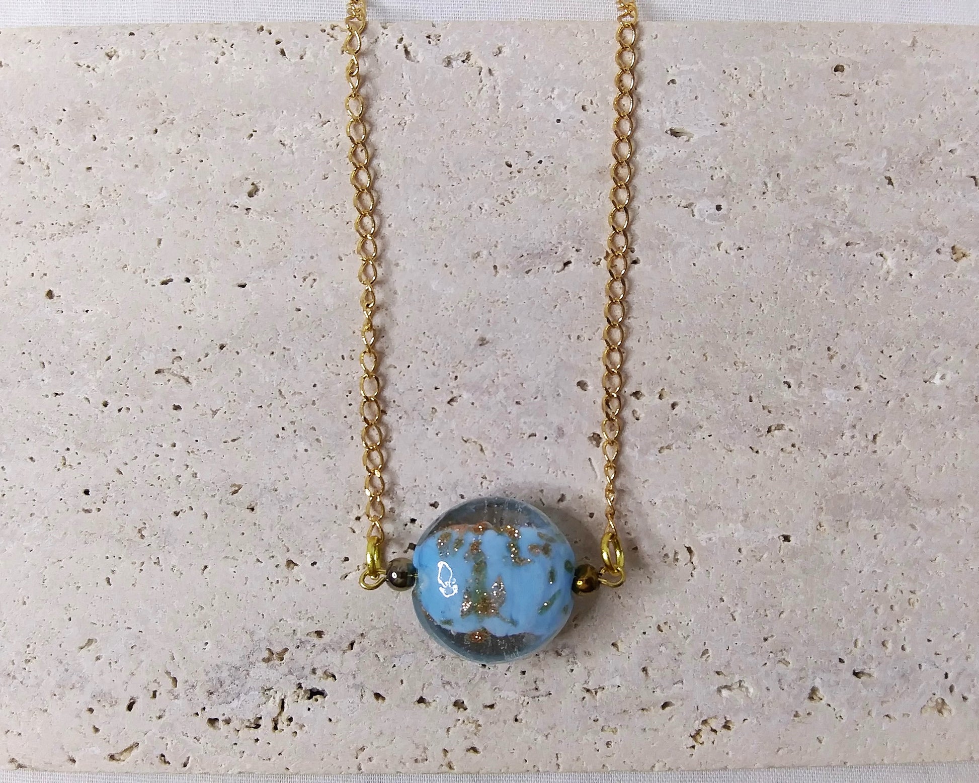 gold chain necklace with a light blue glitter dust pendant