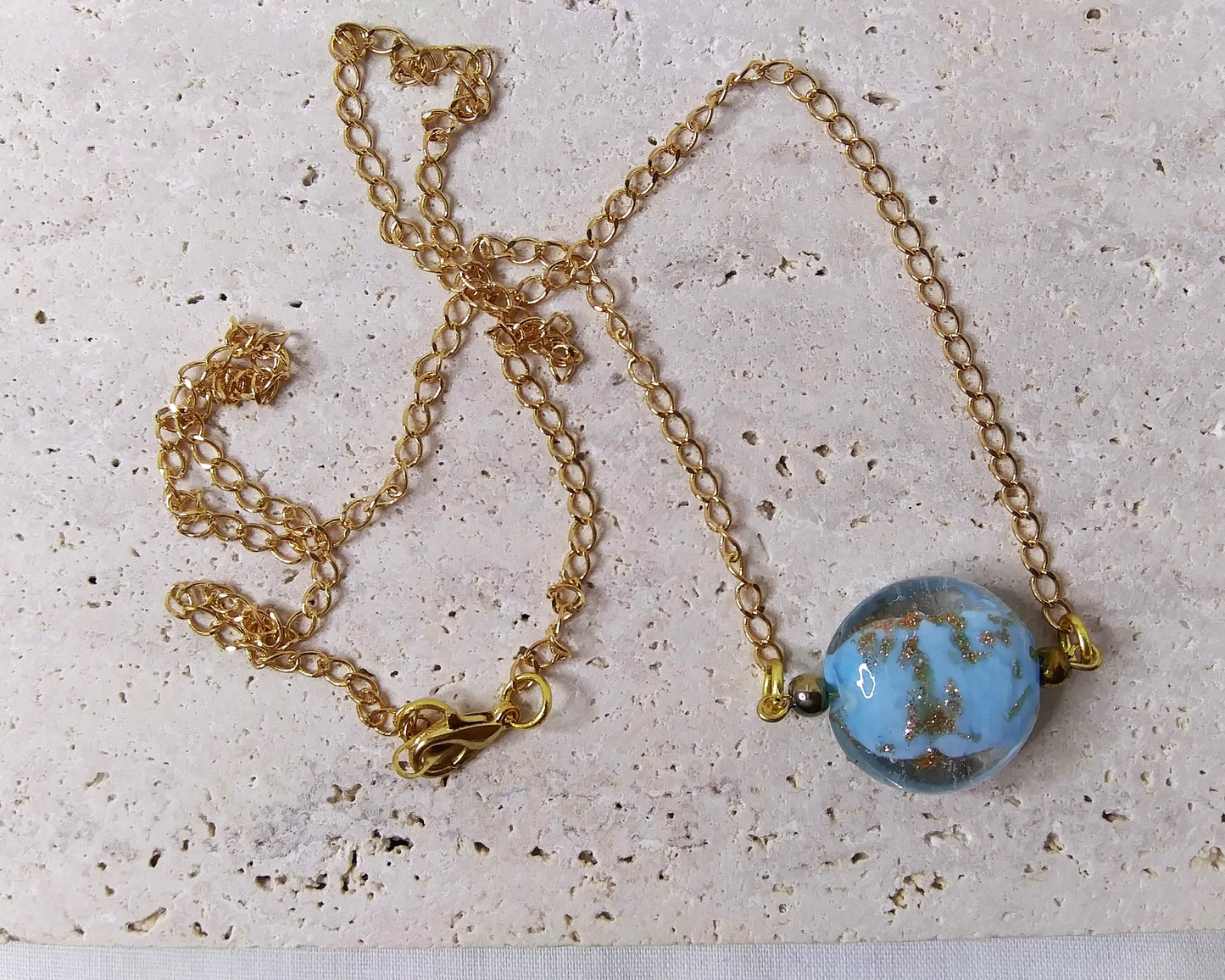 gold chain necklace with a light blue glitter dust pendant